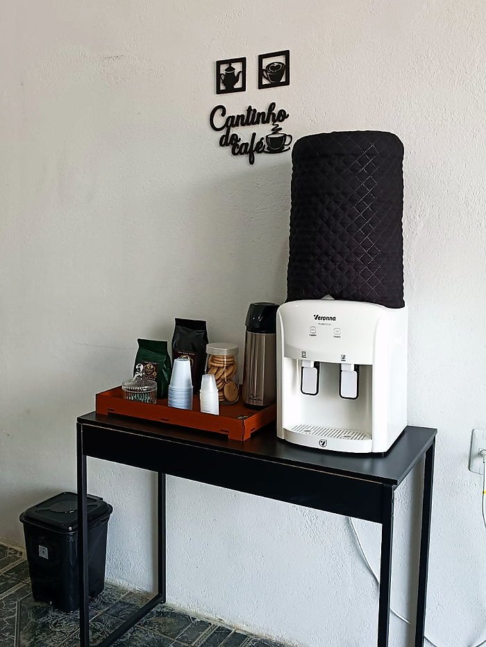 Cantinho do café do escritório, com garrafa térmica, copos e bebedouro